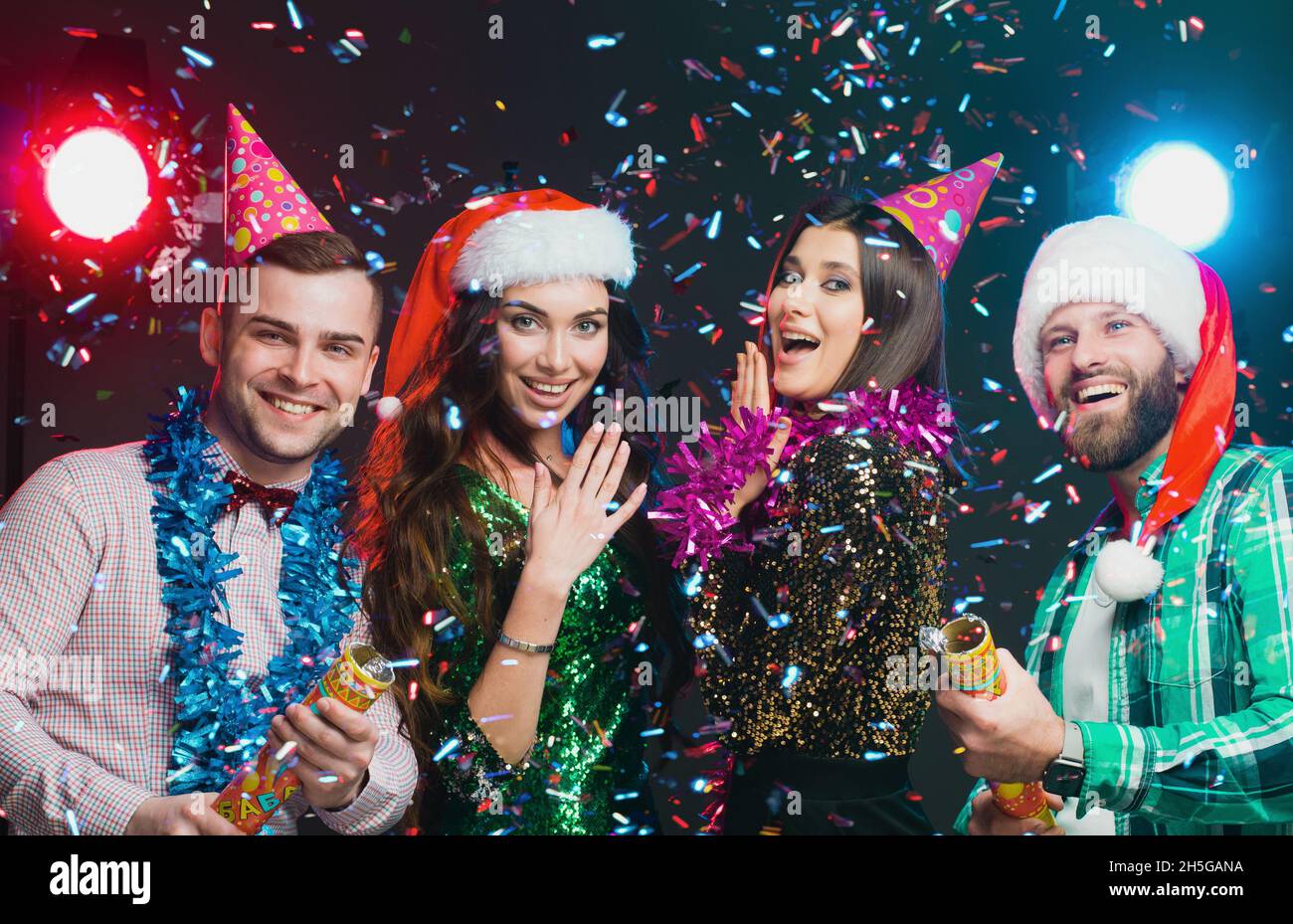 Party Poppers. Silvesterparty der besten Freunde. Eine Gruppe junger Menschen mit Neujahrs- und Geburtstagsmützen Stockfoto