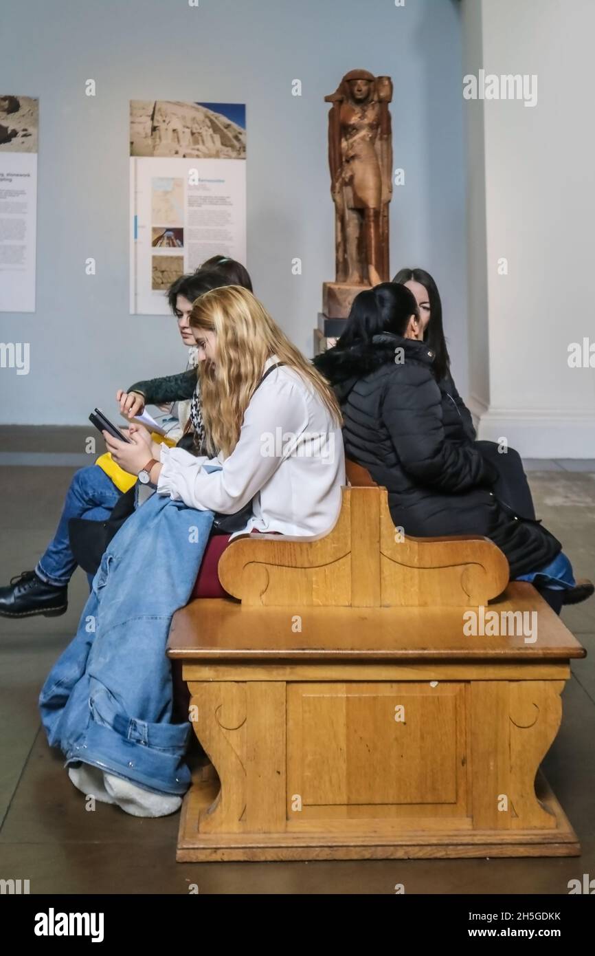 London UK 1 -13 -2018 Schulkinder - Jugendliche besuchen das Museum, aber sitzen und schauen sich das Telefon an, anstatt sich umzusehen Stockfoto
