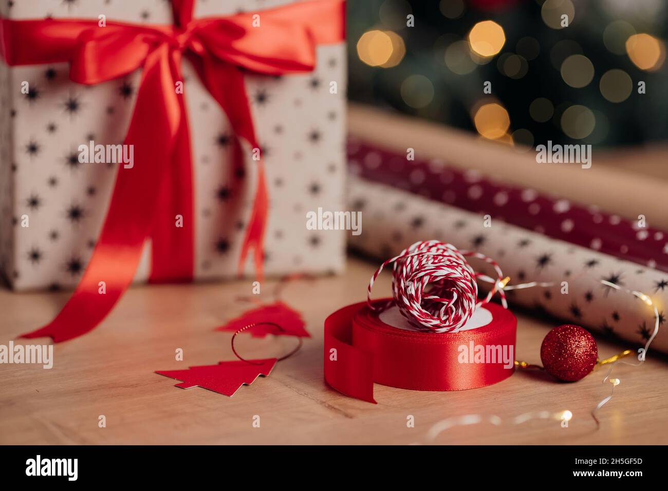 Schöne Weihnachts-Geschenkbox in Kraftpapier und rotem Band auf dem Hintergrund von weihnachtsbaum und Lichter eingewickelt. Präsentiert die Vorbereitung Stockfoto