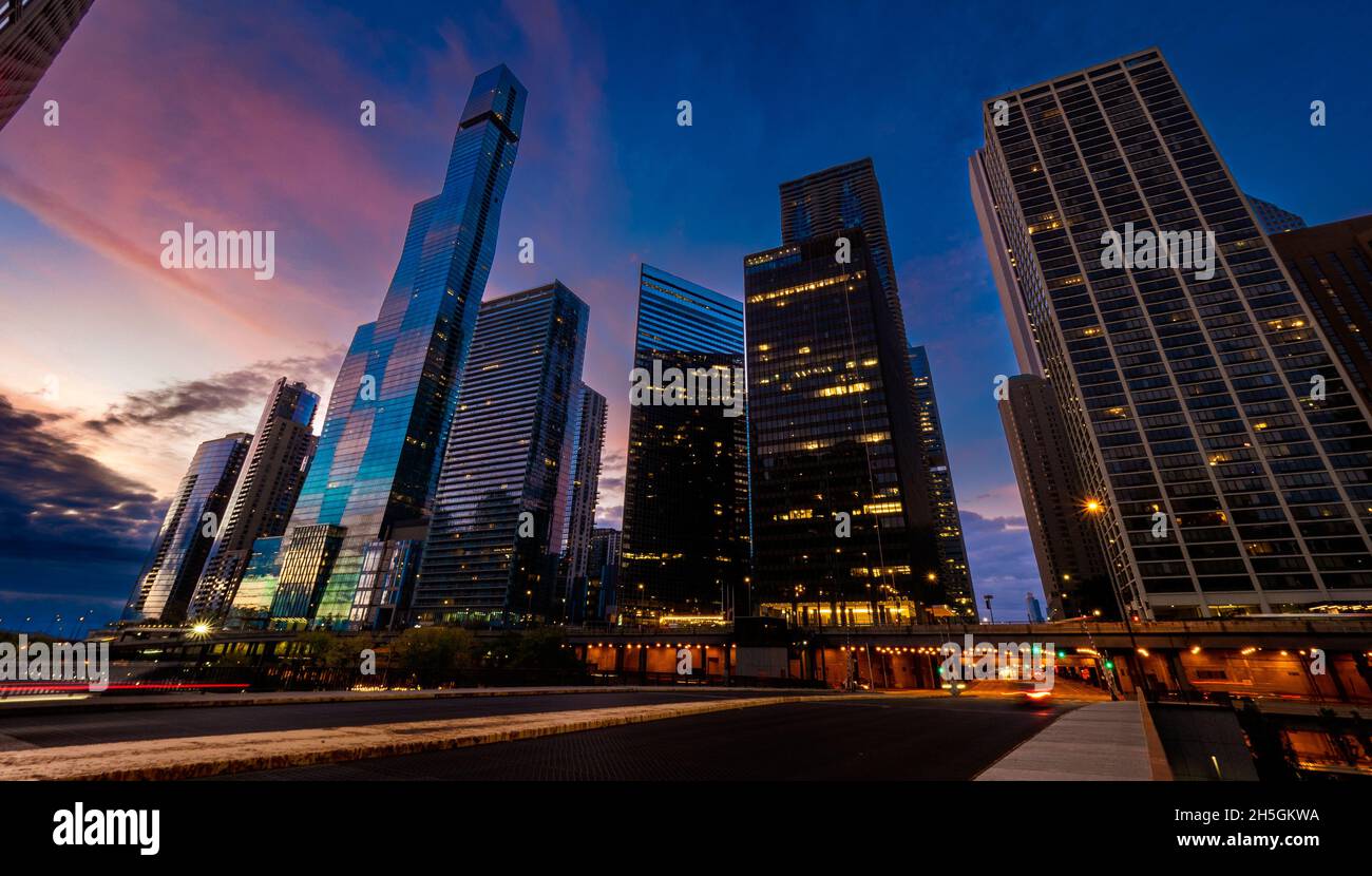 Blick am frühen Morgen auf die Glasfassaden von Wolkenkratzern, die den blauen und rosafarbenen Himmel bei Sonnenaufgang in der Innenstadt von Chicago, IL, USA, reflektieren Stockfoto