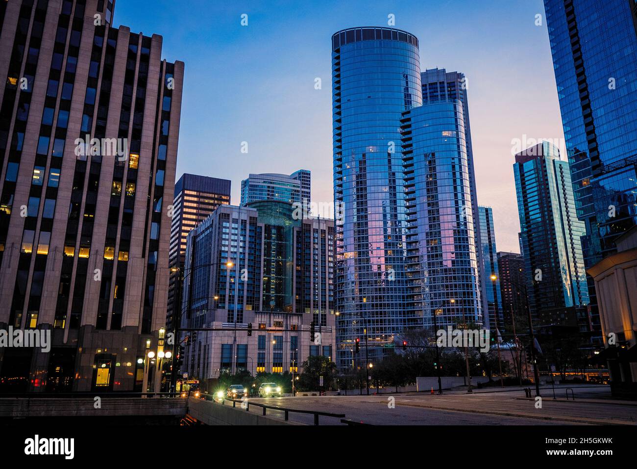 Blick am frühen Morgen auf die Glasfassaden von Wolkenkratzern, die den blauen und rosafarbenen Himmel bei Sonnenaufgang in der Innenstadt von Chicago, IL, USA, reflektieren Stockfoto