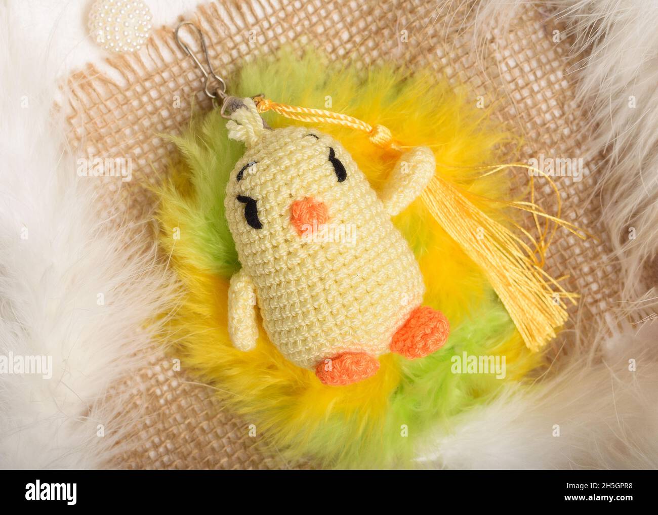 Küken in Amigurumi-Häkeltechnik mit den vorherrschenden Farben gelb, grün und orange. Handgemachtes Strickspielzeug. Amigurumi Spielzeug. Gefülltes Häkeln Stockfoto