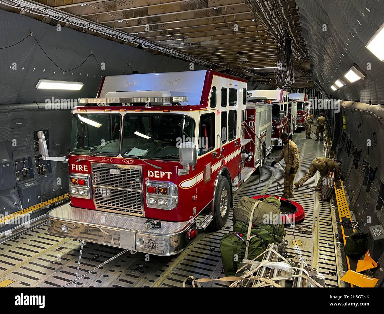 Mitglieder der 120. Luftbrücke und des 60. Luftmobilitätsflügels laden auf der Montana Air Guard Base, Great Falls, Mt, 6. November 2021, einen Feuerwehrwagen des Spartan Guardian auf eine US Air Force C-5M Super Galaxy. Im Rahmen des Denton-Programms des Verteidigungsministeriums, das humanitäre Hilfsgüter in der ganzen Welt zur Verfügung stellt, laden die Flieger des 120. Luftlift-Flügels und des 60. Luftmobilitätsflügels drei Feuerwehrfahrzeuge auf eine C-5M Super Galaxy Foto der Air National Guard von Tech. Sgt. Joesph Davis) Stockfoto