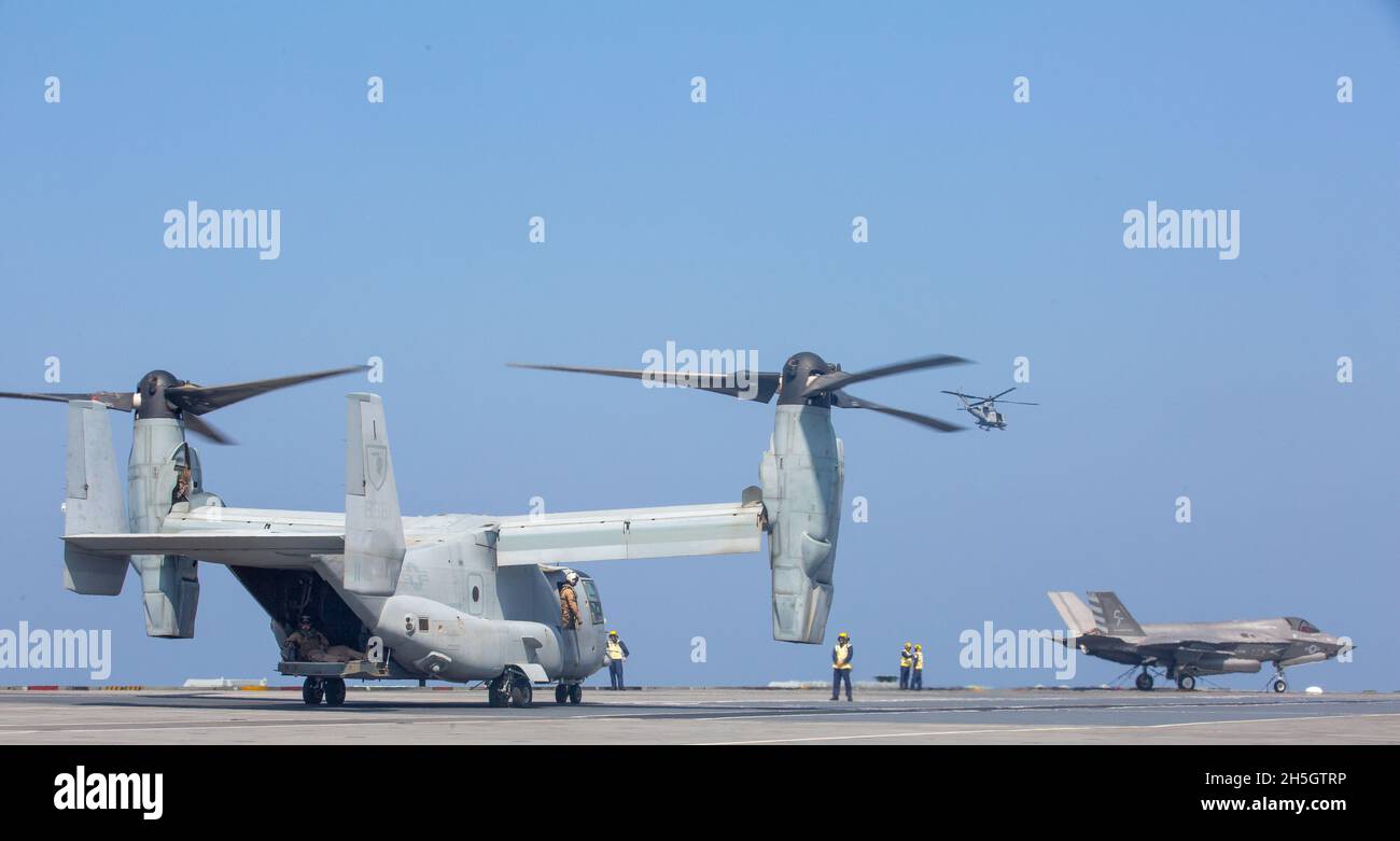 US-Marineinfanteristen, die ein UH-1Y-Gift an Marine Medium Tiltrotor Squadron 165 (verstärkt), 11. Marine Expeditionary Unit, fliegen am 8. November 2021 an der HMS Queen Elizabeth im Arabischen Meer vorbei. Gleichzeitig kreuzte Marine Fighter Attack Squadron 211 F-35B Lightning II’s an die USS Essex (LHD 2). Die Entwicklung zeigte eine erhöhte Interoperabilität, einen Informationsaustausch und einen erweiterten Zugang in der gesamten Region als Verbündete sowie glaubwürdige und fähige Kräfte, die im Einsatzgebiet der 5. Flotte der USA tätig sind. Stockfoto