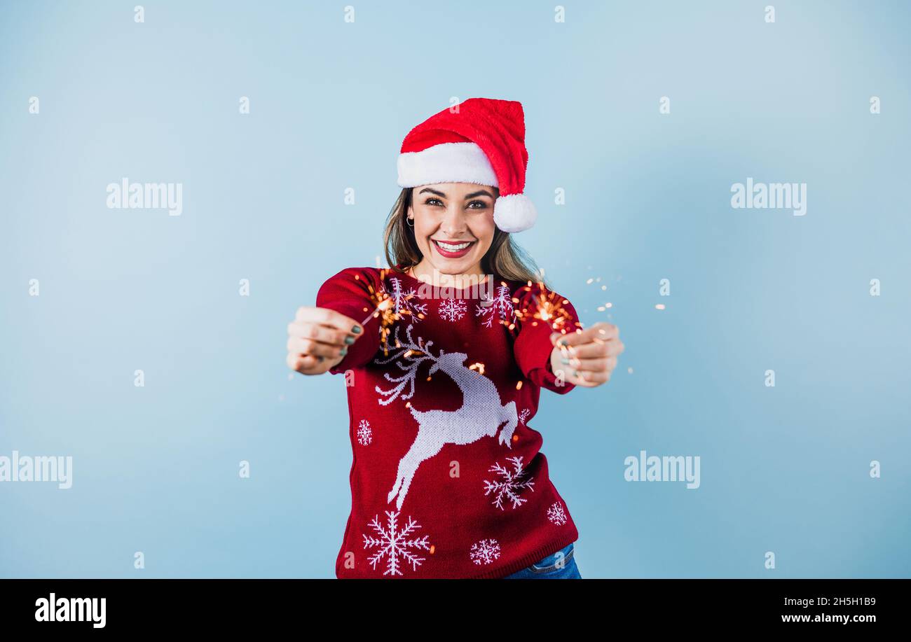 Erwachsene hispanische Frau hält weihnachten funkelnde Lichter für mexikanische posada in weihnachten auf gelblichem Hintergrund in Mexiko Lateinamerika Stockfoto