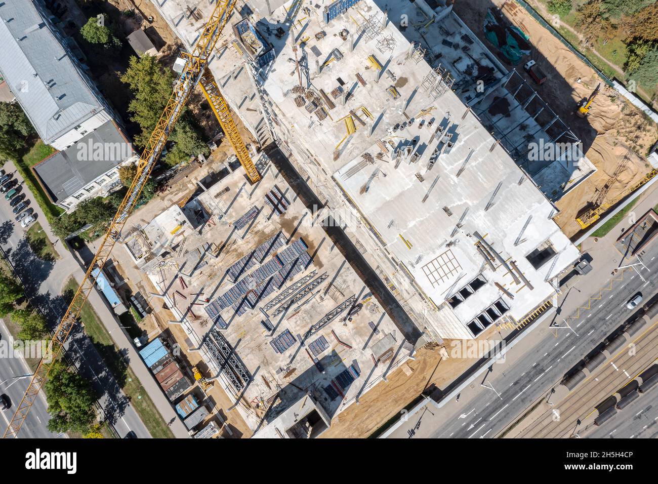 Luftaufnahme von oben auf der geschäftigen Baustelle. Arbeiten Baumaschinen und Baustoffe. Stockfoto