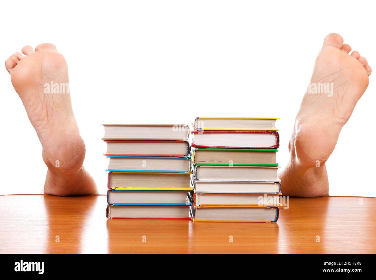 Bücher und gefallener Mensch unter dem Tisch auf dem weißen Hintergrund Stockfoto