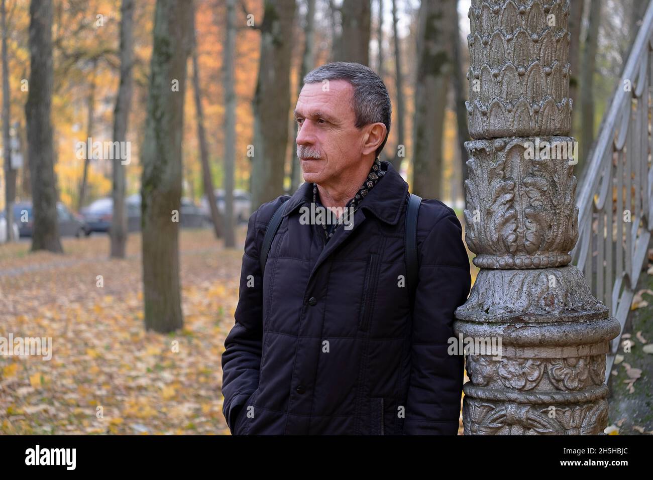 Älterer pensionierter Mann an einem schönen Herbsttag im Park steht und ruht Stockfoto