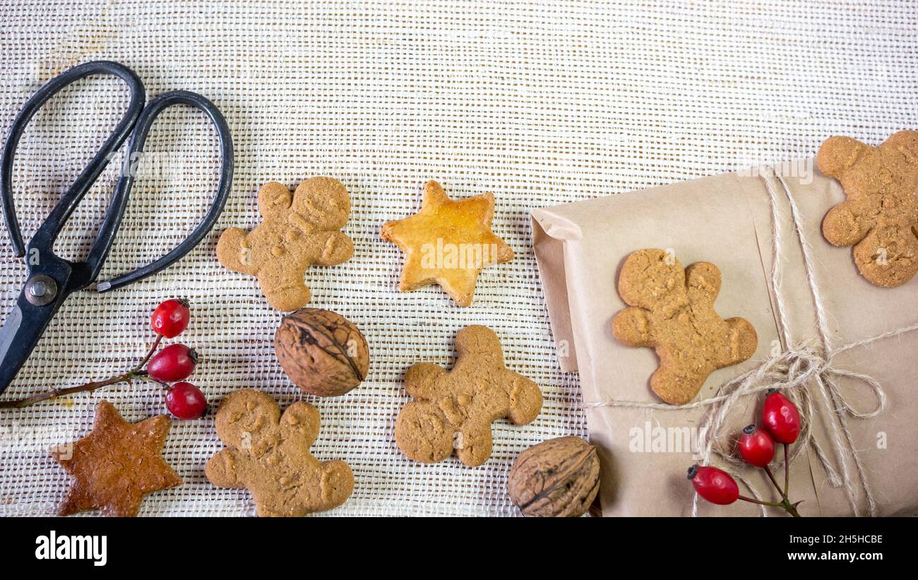 Home Backed Ingwer Mann Cookies, Recycling-Papier Geschenkverpackung, Dekoration für Weihnachten, Schere, auf einem rustikalen Stoff Hintergrund. Nahaufnahme. Stockfoto