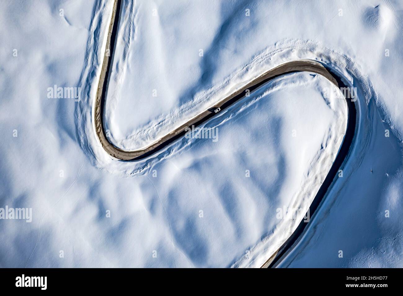 Auto auf der S-förmigen Straße in den schneebedeckten Bergen von oben, Luftbild, Dolomiten, Italien Stockfoto