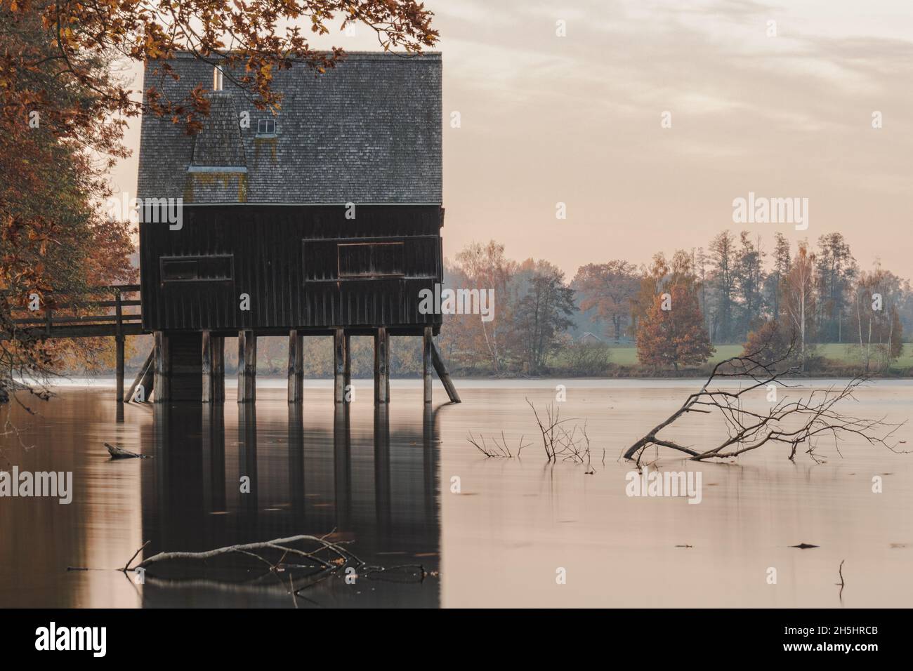 Altes Fischerhaus bei Sonnenaufgang an einem See in Deutschland. Stockfoto