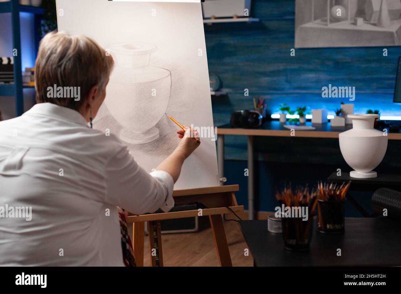 Kaukasisch alter Künstler, der mit Vase und Bleistift auf Leinwand für authentisches Zeichnen in der Werkstatt arbeitet. Ältere Frau mit künstlerischem Hobby Meisterwerk für Bildende Kunst-Projekt im Studio zu schaffen Stockfoto