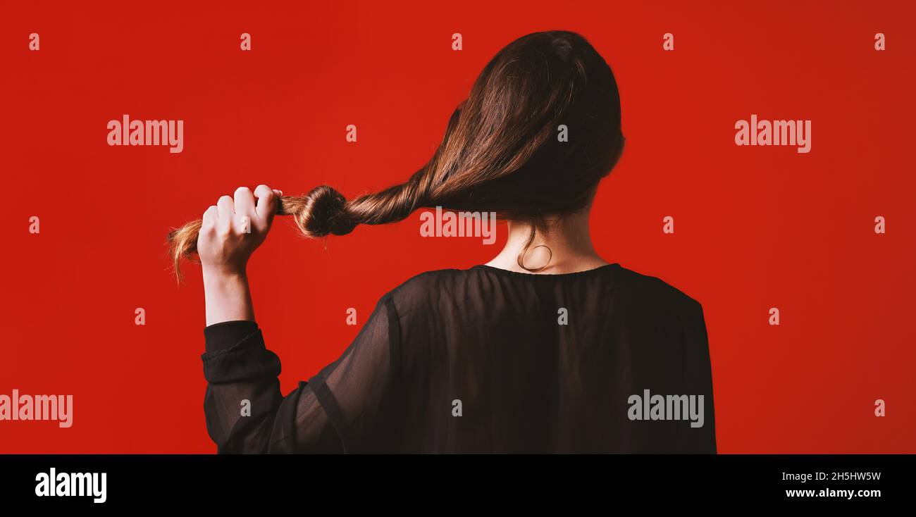 Brunette Frau zieht ihre langen Haare mit Knoten es Stockfoto