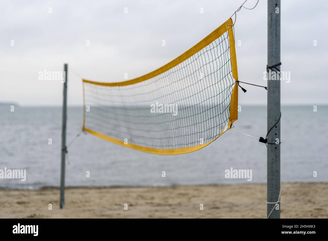 Volleyballnetz am Strand in der Nähe des Meeres an launisch bewölktem Tag. Niemand in der Nähe Stockfoto