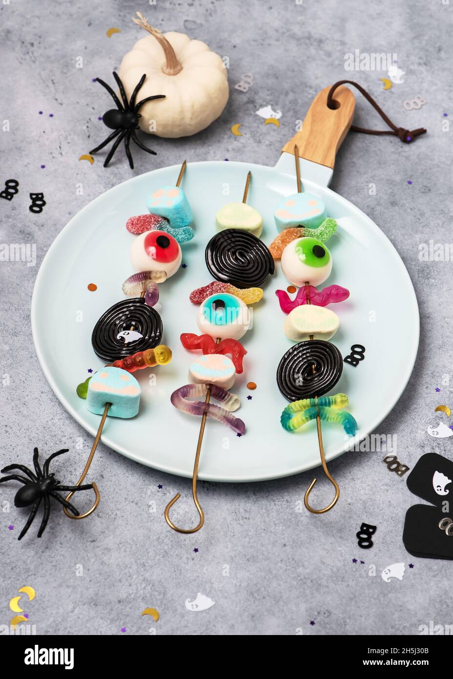 Teller mit Spiessen aus buntem Gelee, Augäpfeln, Süßigkeiten und Marschwalben. Süße Halloween Kinder Party Food Konzept. Speicherplatz kopieren. Stockfoto