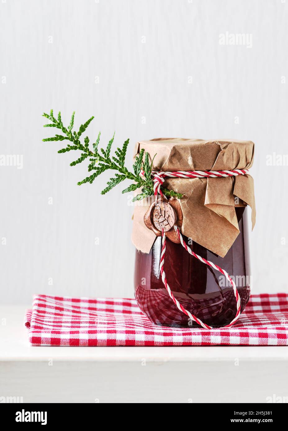 Hausgemachte süße Bio-Pflaumenkonfitüre in einem Glas, das mit Grunge-Papier und Wachssiegel verziert ist. Weihnachten und Winterurlaub einfache Geschenke Idee. Stockfoto
