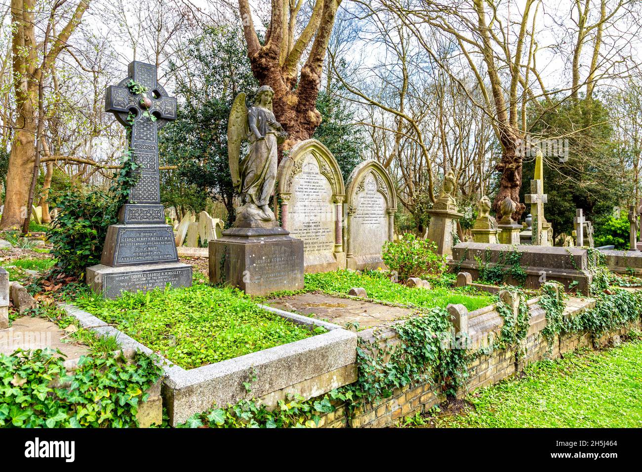Eine Reihe von Gräbern und ein keltisches Kreuz auf dem Highgate Cemetery East, London, Großbritannien Stockfoto