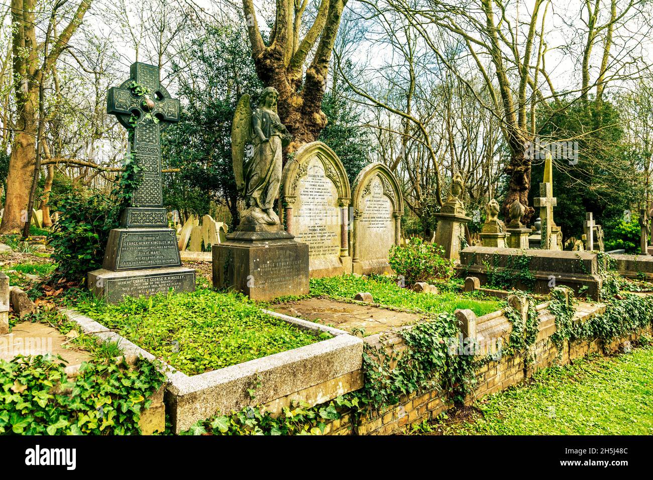 Eine Reihe von Gräbern und ein keltisches Kreuz auf dem Highgate Cemetery East, London, Großbritannien Stockfoto