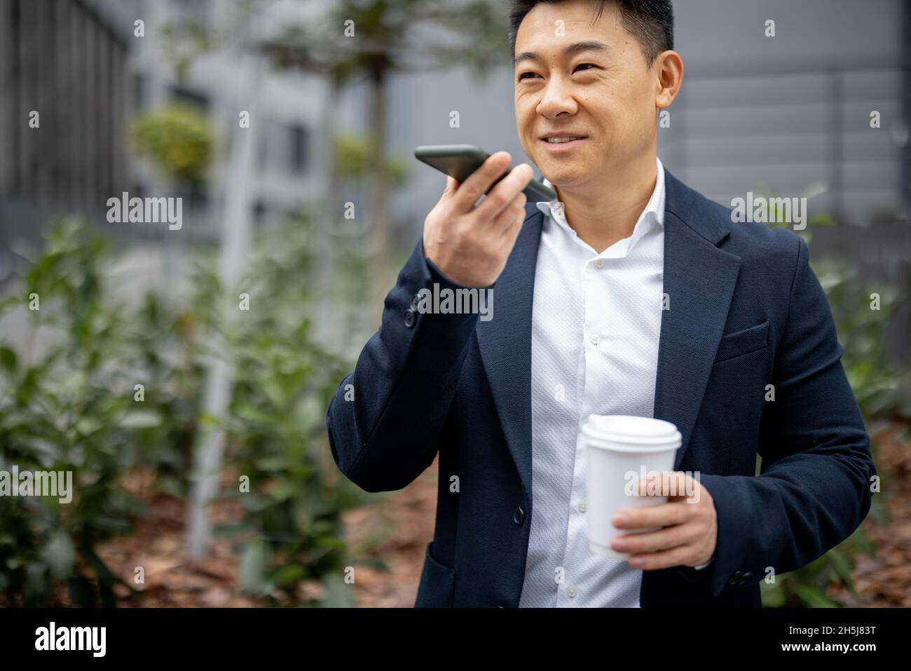 Geschäftsmann mit Kaffeetasse, die auf dem Smartphone anruft Stockfoto