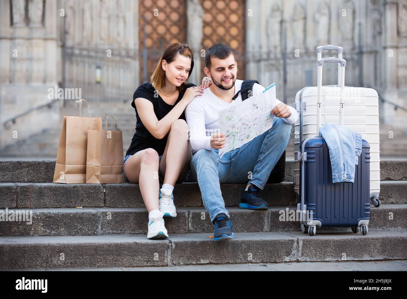 Positiver Mann und Frau sitzen an der Treppe mit Karte Stockfoto