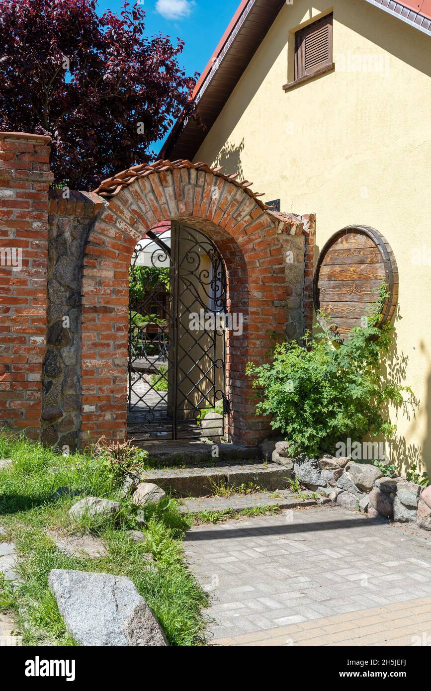 Ziegelbogen mit schmiedeeisernem Gitter, Eingang im Hof des Hauses. Das Konzept der Vintage-Architektur. Stockfoto