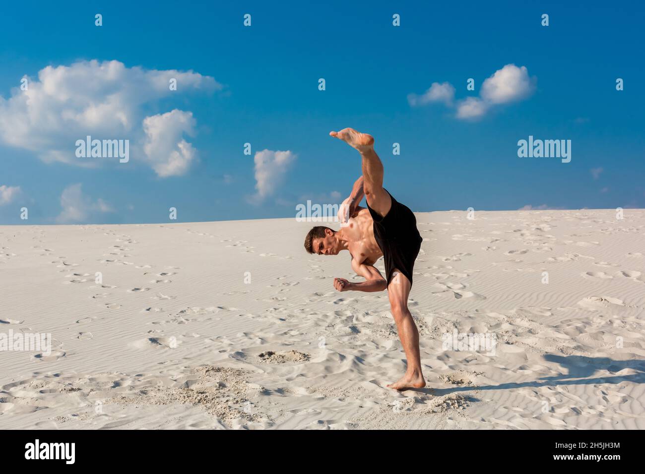 Porträt der jungen parkour Mann tun, Flip oder Salto auf dem Sand. Stockfoto