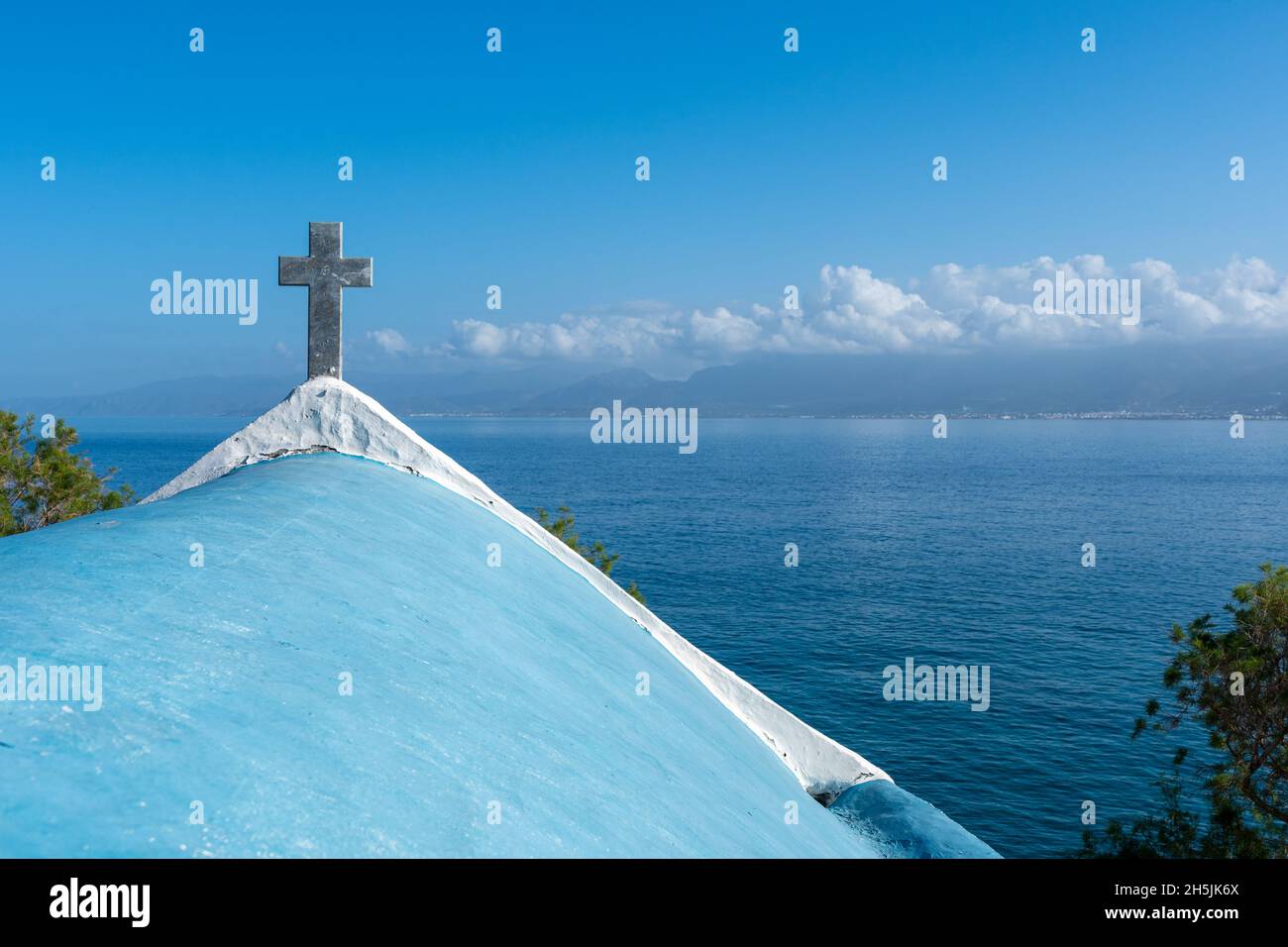 Steinkreuz über der weißen griechischen Kirche in blauem Himmel. Stockfoto