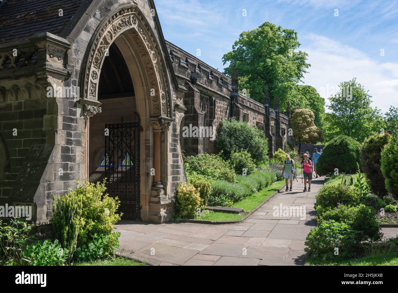 Ruhestand, Blick im Sommer auf ein aktives Seniorenpaar, das sich der Veranda der mittelalterlichen Holy Trinity Parish Church in Skipton, Yorkshire, England nähert Stockfoto