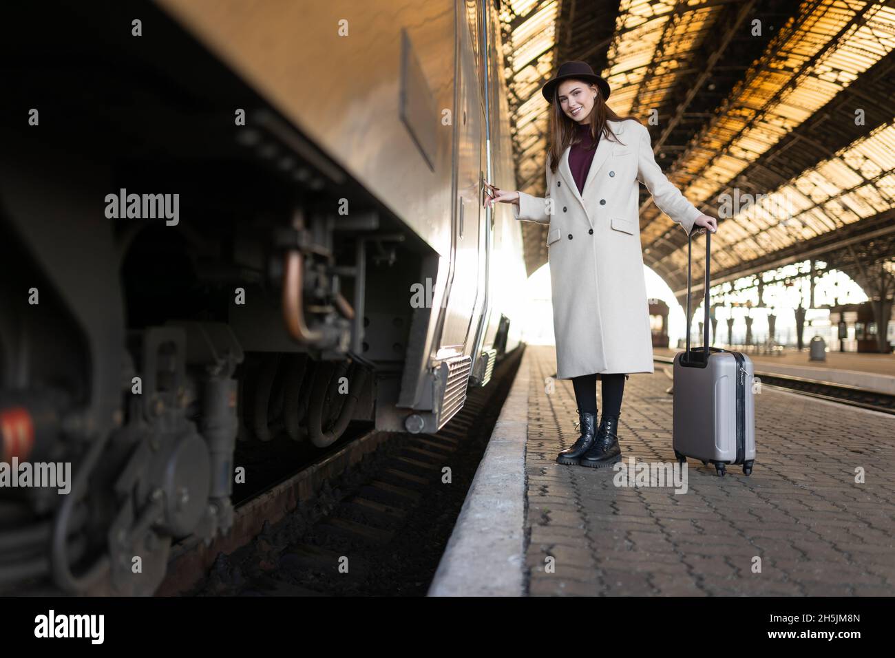 Eine fröhliche Frau drückt den Knopf an der Zugtür, um einzutreten Stockfoto