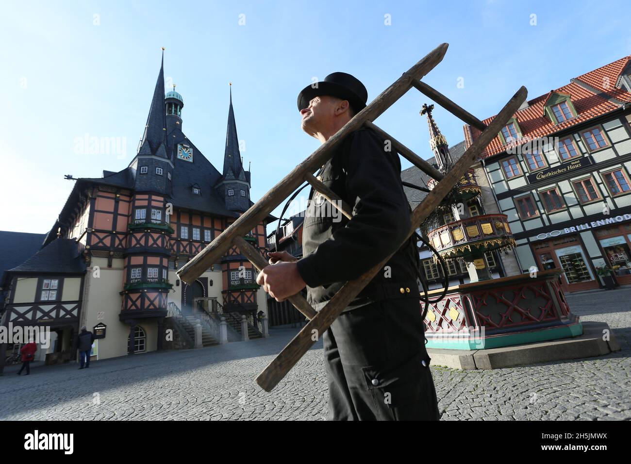 Wernigerode, Deutschland. November 2021. Vor einem Mehrfamilienhaus auf dem Marktplatz steht ein Schornsteinfeger. Die glücklichsten Menschen in Deutschland leben in Sachsen-Anhalt und Schleswig-Holstein. Der Umfrage zufolge ist die Lebenszufriedenheit hier am höchsten. Das ist das Ergebnis des neuen aktuellen Glücksatlasses über das Glücksniveau der Deutschen. Quelle: Matthias Bein/dpa-Zentralbild/dpa/Alamy Live News Stockfoto