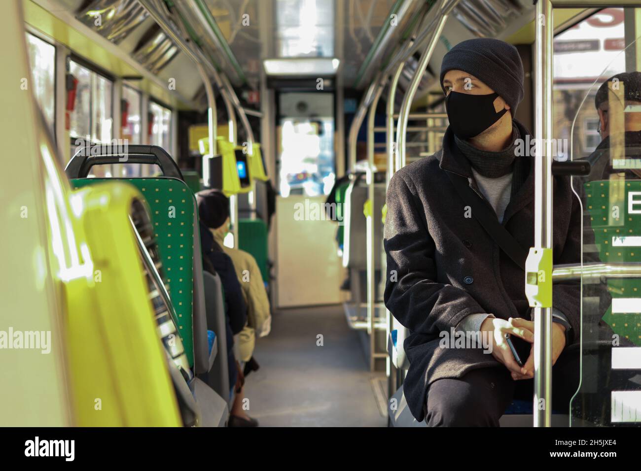 Mehrjähriger europäischer Mann mit Gesichtsmaske, der mit dem Bus in öffentlichen Verkehrsmitteln unterwegs ist Stockfoto