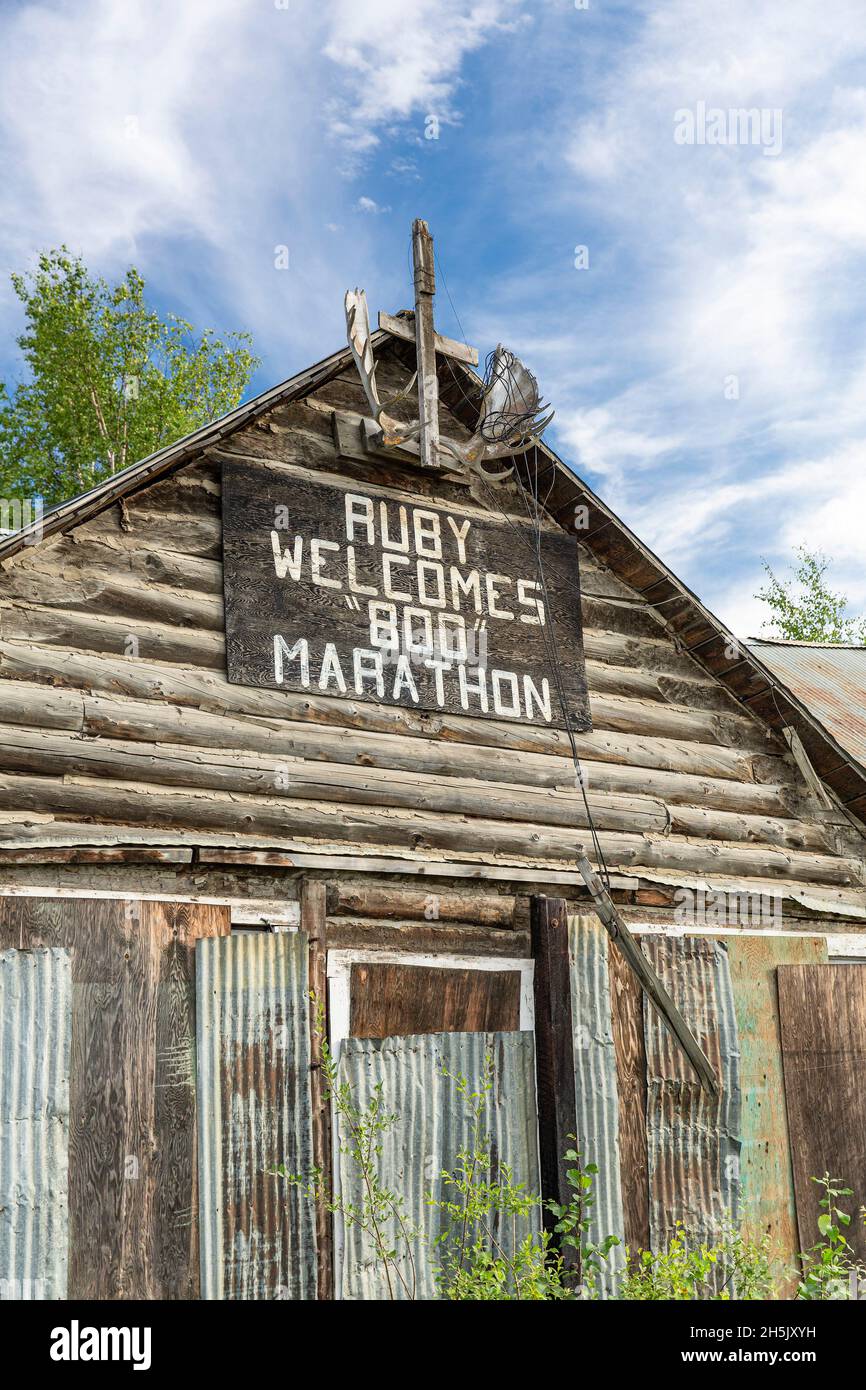 Ein Schild für den „Ruby Signes 800 Marathon“ ist im Sommer auf einer alten Blockhütte, Ruby, Interior Alaska, USA, ausgestellt Stockfoto