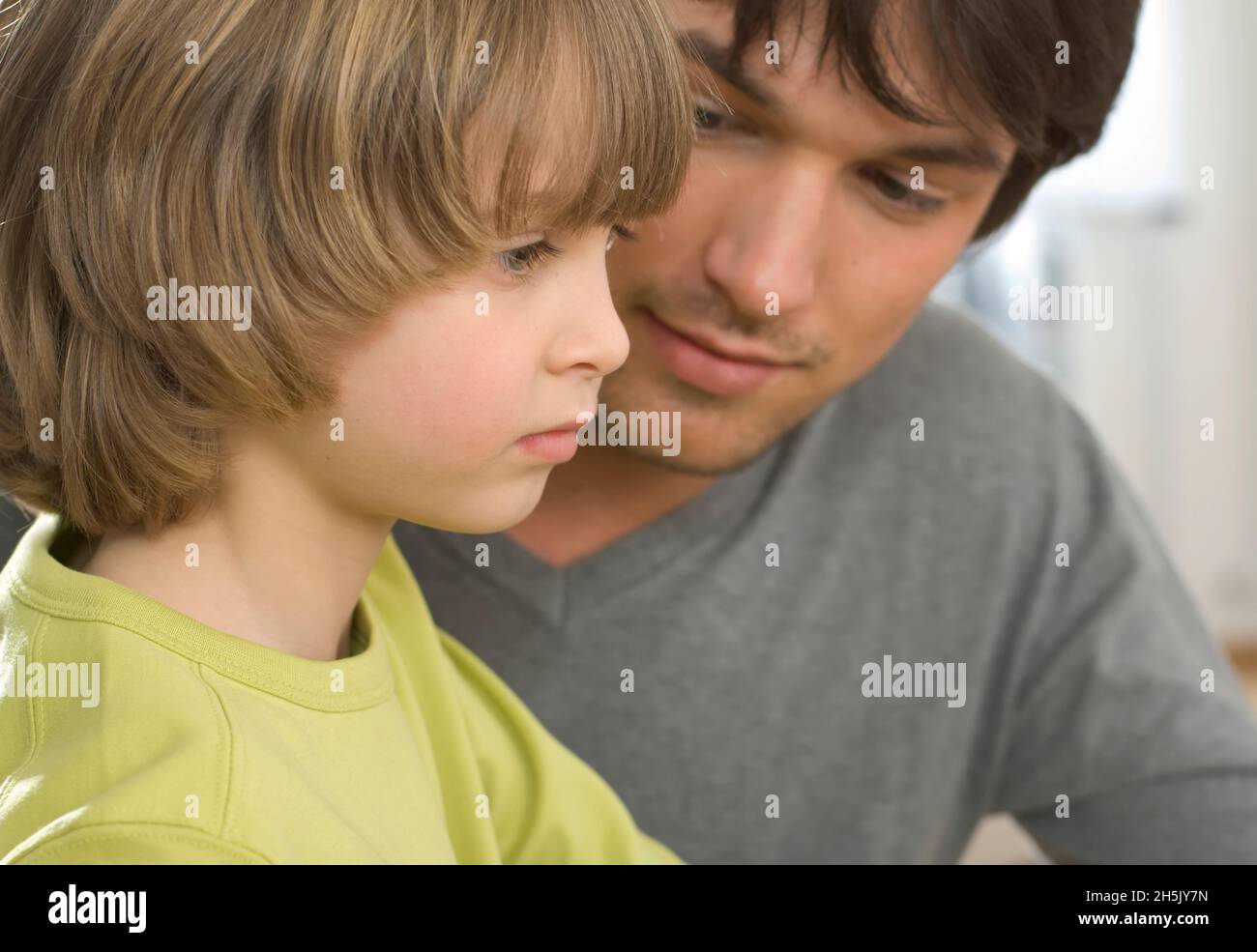 Nahaufnahme des Vaters, der den Sohn beim Konzentrieren beobachtet; Deutschland Stockfoto