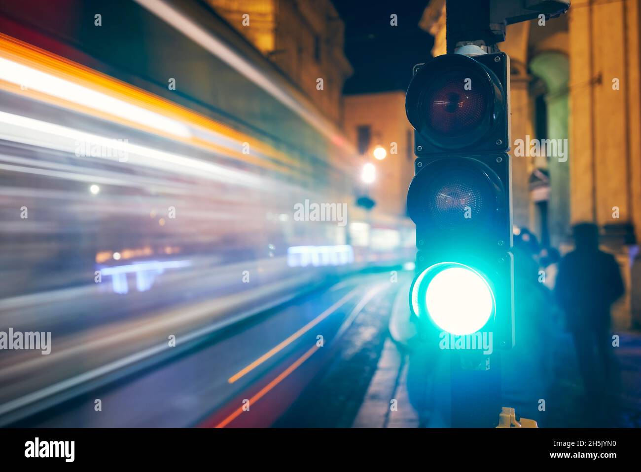 Grün auf Ampel gegen leichte Spuren von Straßenbahn und Autos. Nachtszene der Straße in Prag, Tschechische Republik. Stockfoto