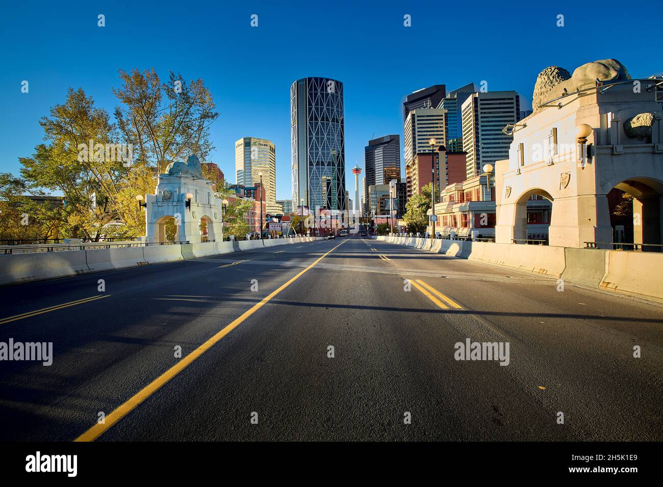 Skyline von Downtown Calgary von der Center Street Bridge mit Bow River und blauem Himmel in Alberta, Kanada. Stockfoto