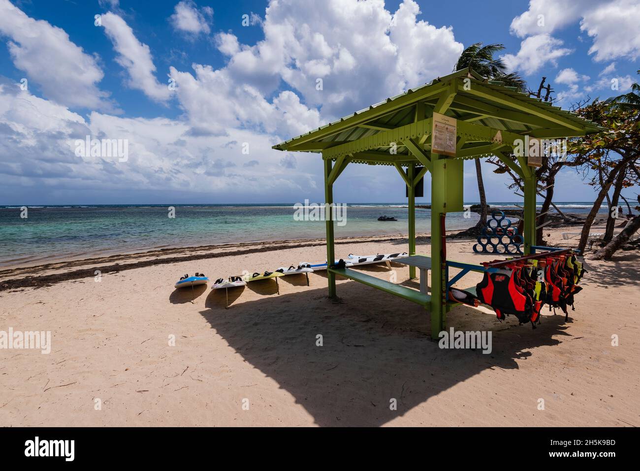 Pavillon mit Schwimmwesten und Wasserbrettern zum Mieten am sandigen Strand Plage de la Caravelle am Ufer der Karibik, Sainte-Anne auf der... Stockfoto