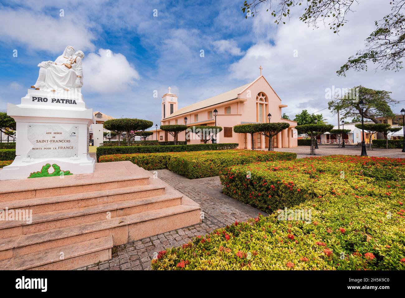 Die Kirche des heiligen Franziskus von Assisi, die 1932 wieder aufgebaut wurde, mit dem Kirchplatz und dem Kriegsdenkmal im Vordergrund in der Stadt Saint Francois, Grande-Terre Stockfoto