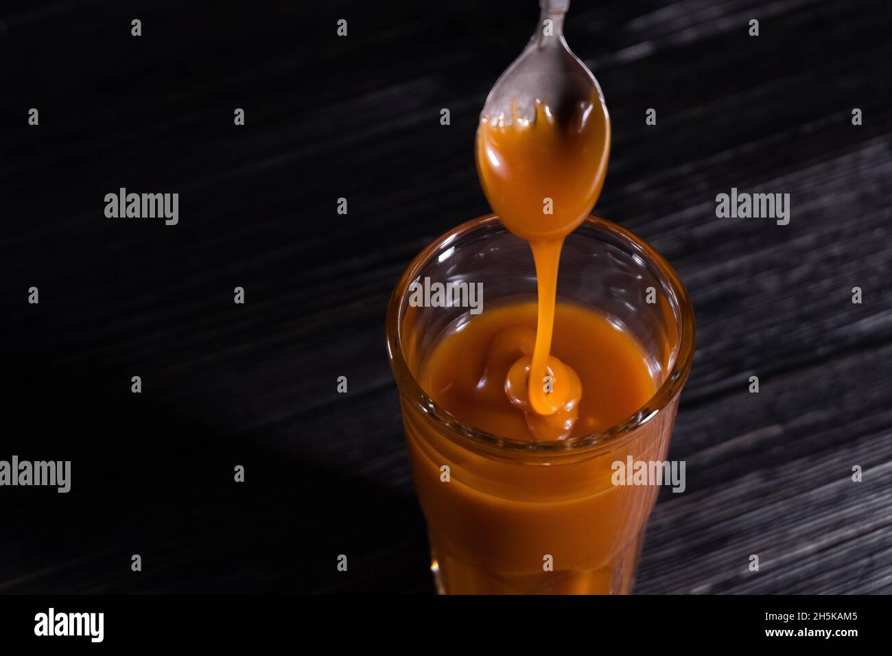 Hausgemachte gesalzene Karamellsauce in einem Glas auf dunklem Hintergrund. Text kopieren Stockfoto