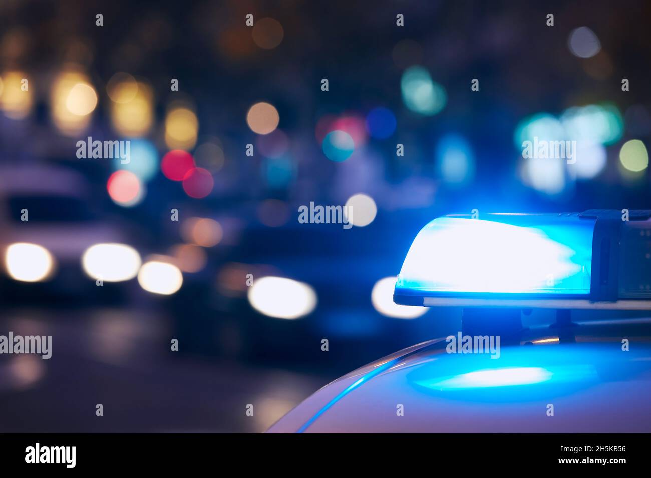 Blaues Flasher-Licht der Sirene des Polizeiautos auf der nächtlichen Stadtstraße. Themen Kriminalität, Notfall und Hilfe. Stockfoto