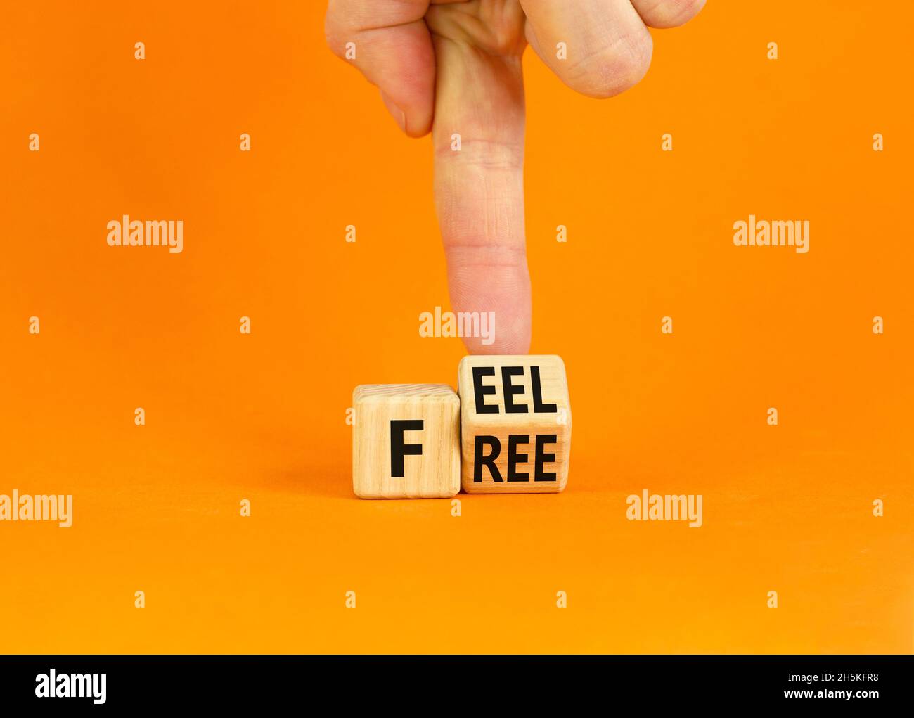 Symbol „Feel free“. Geschäftsmann dreht einen Holzwürfel mit den Worten „Feel free“ auf einem schönen orangefarbenen Tisch mit orangefarbenem Hintergrund. Speicherplatz kopieren. Psycholog Stockfoto