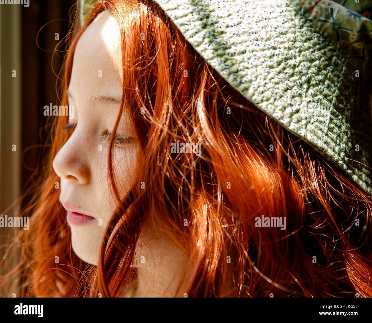 Nahaufnahme eines kleinen Mädchens in grünem Hut mit leuchtend roten Haaren Stockfoto