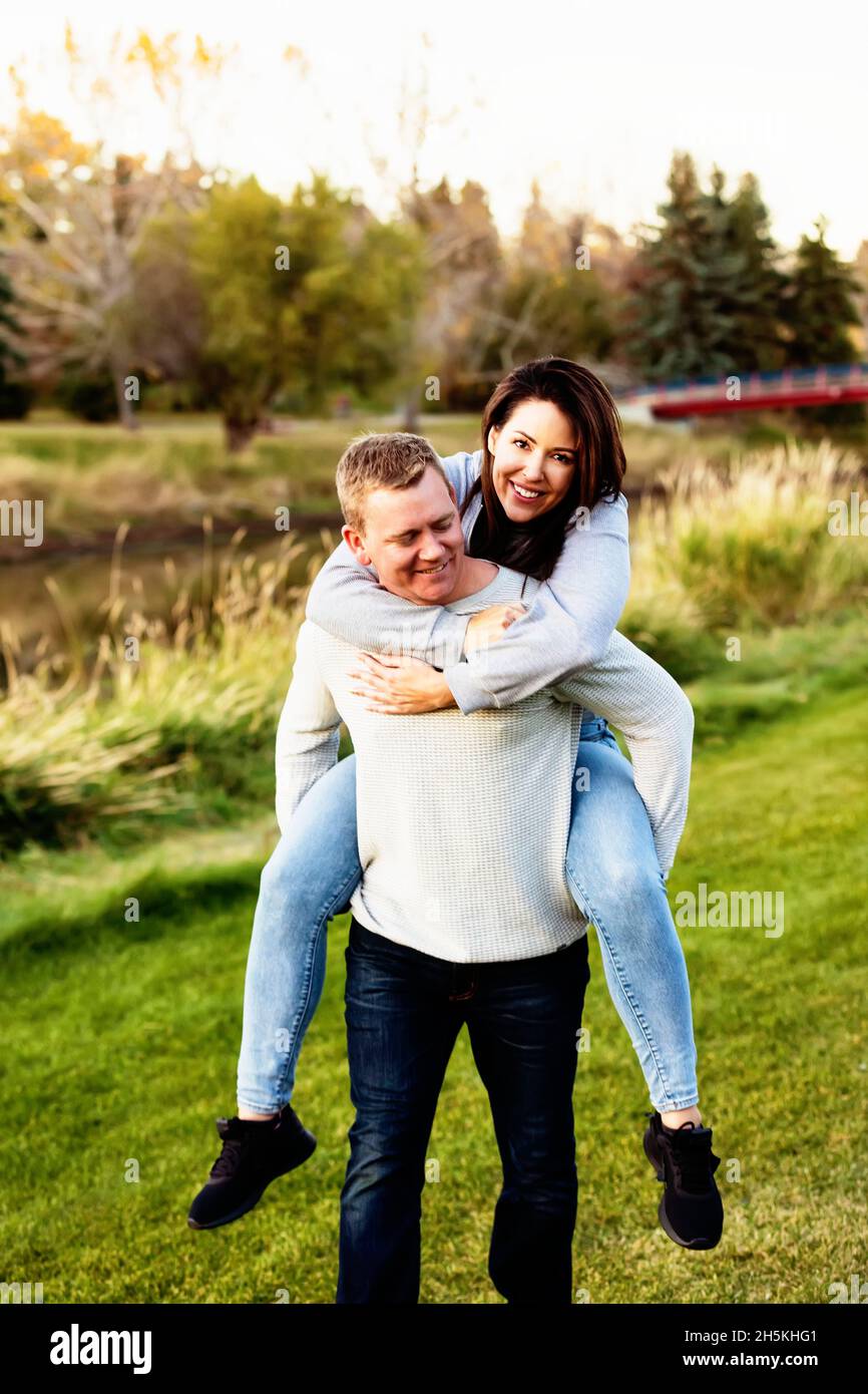 Porträt eines Ehepaares mittlerer Erwachsene, das im Herbst in einem Park Spaß hat; St. Albert, Alberta, Kanada Stockfoto