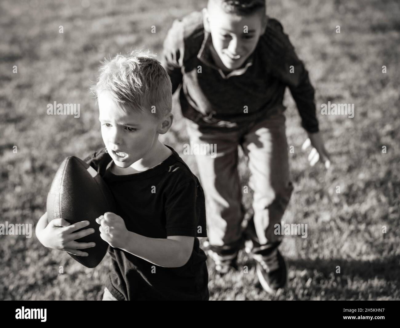 Zwei Brüder, die mit einem Fußball auf dem Rasen laufen; St. Albert, Alberta, Kanada Stockfoto