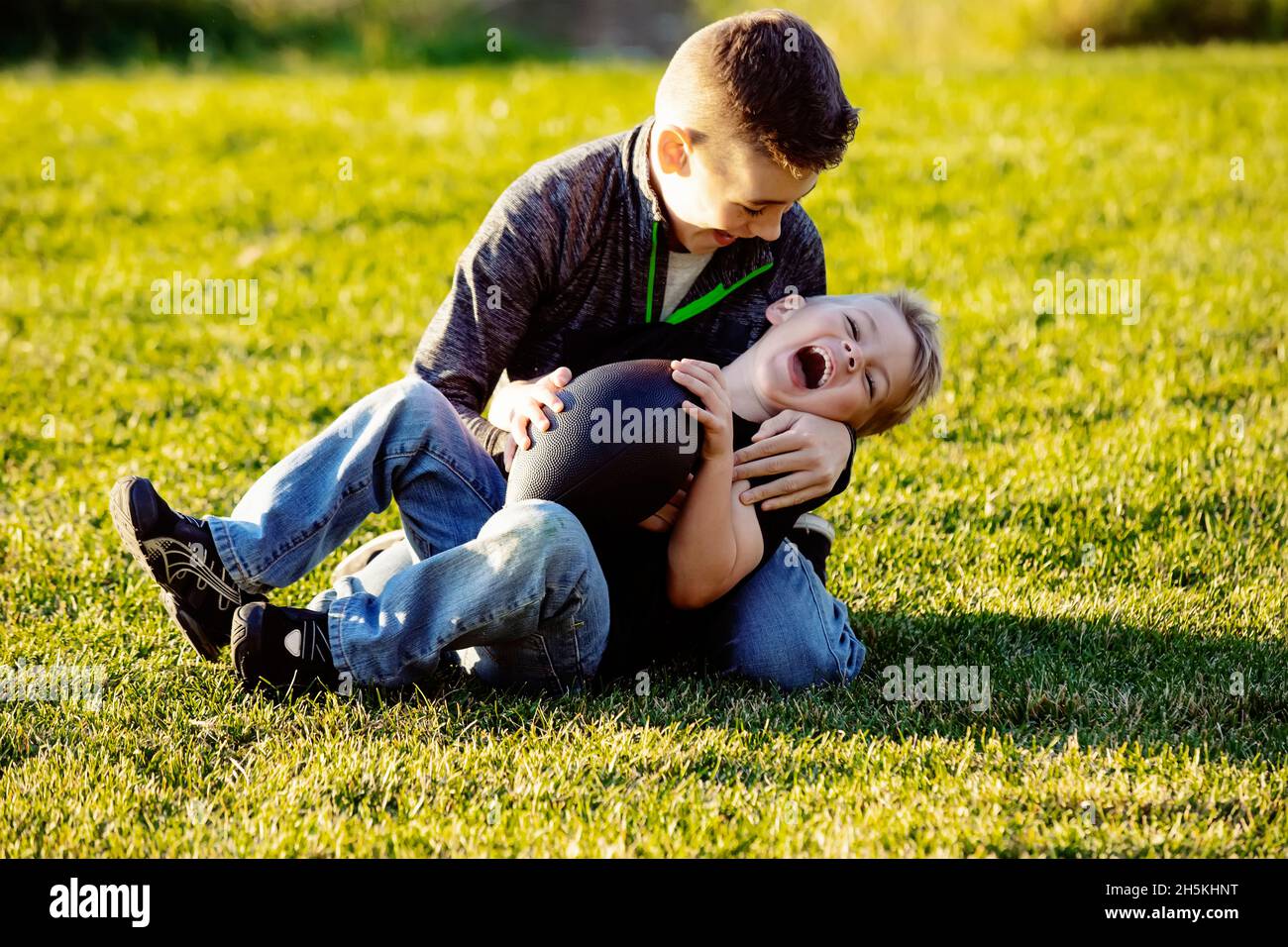 Zwei Brüder, die mit einem Fußball auf dem Rasen aufrauhen; St. Albert, Alberta, Kanada Stockfoto