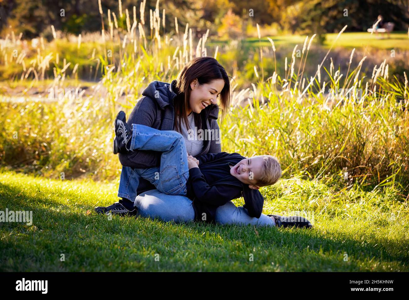 Mutter und Sohn auf dem Rasen in einem Stadtpark; St. Albert, Alberta, Kanada Stockfoto