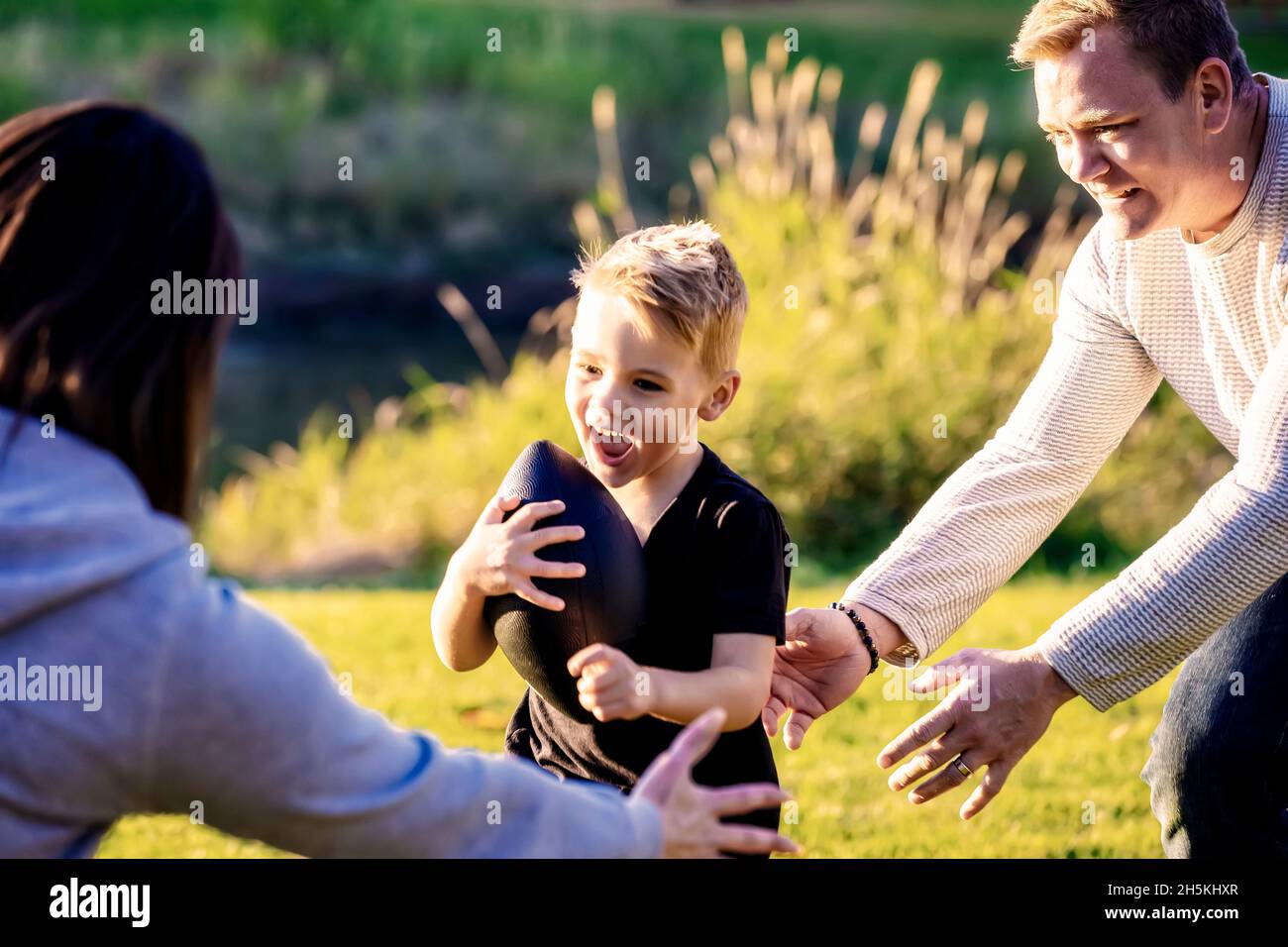 An einem schönen Herbsttag spielt die junge Familie im Park zusammen mit einem Fußball; St. Albert, Alberta, Kanada Stockfoto