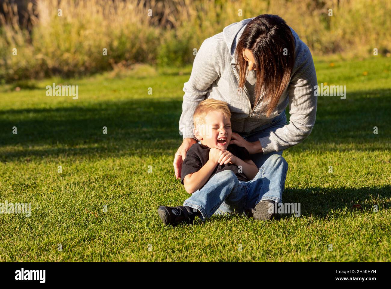 Mutter und Sohn auf dem Rasen in einem Stadtpark; St. Albert, Alberta, Kanada Stockfoto