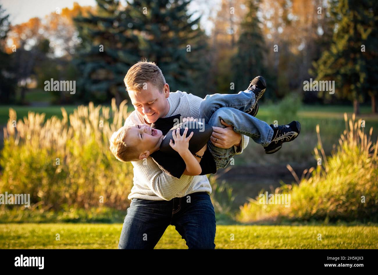 Vater spielt im Herbst mit seinem kleinen Sohn in einem Park; St. Albert, Alberta, Kanada Stockfoto