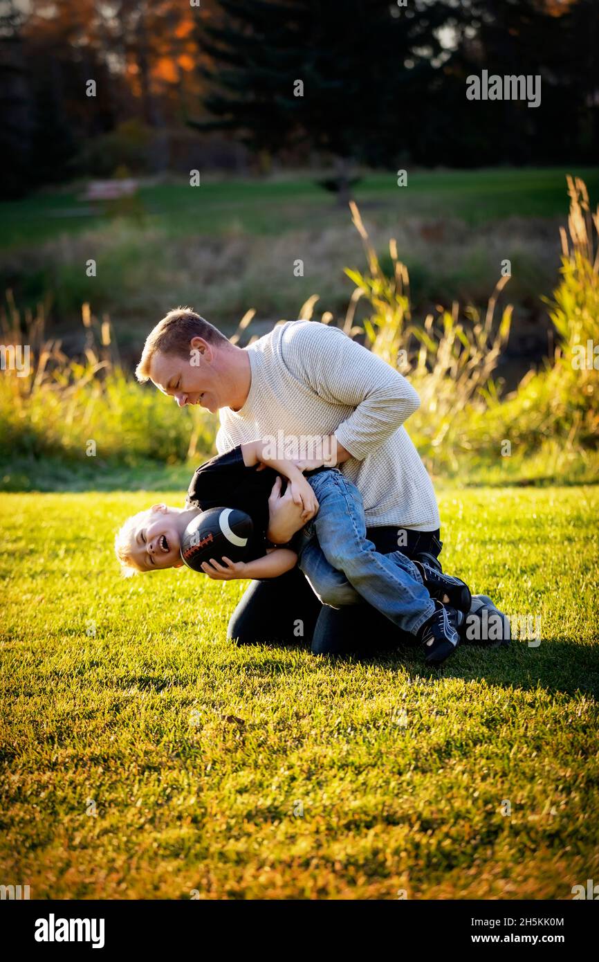 Vater und junger Sohn auf dem Rasen in einem Stadtpark; St. Albert, Alberta, Kanada Stockfoto