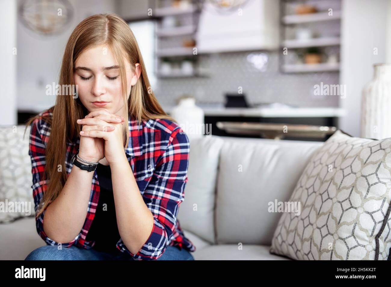 Teenager, die zu Hause auf einer Couch sitzt und Zeit im Gebet verbringt; Edmonton, Alberta, Kanada Stockfoto